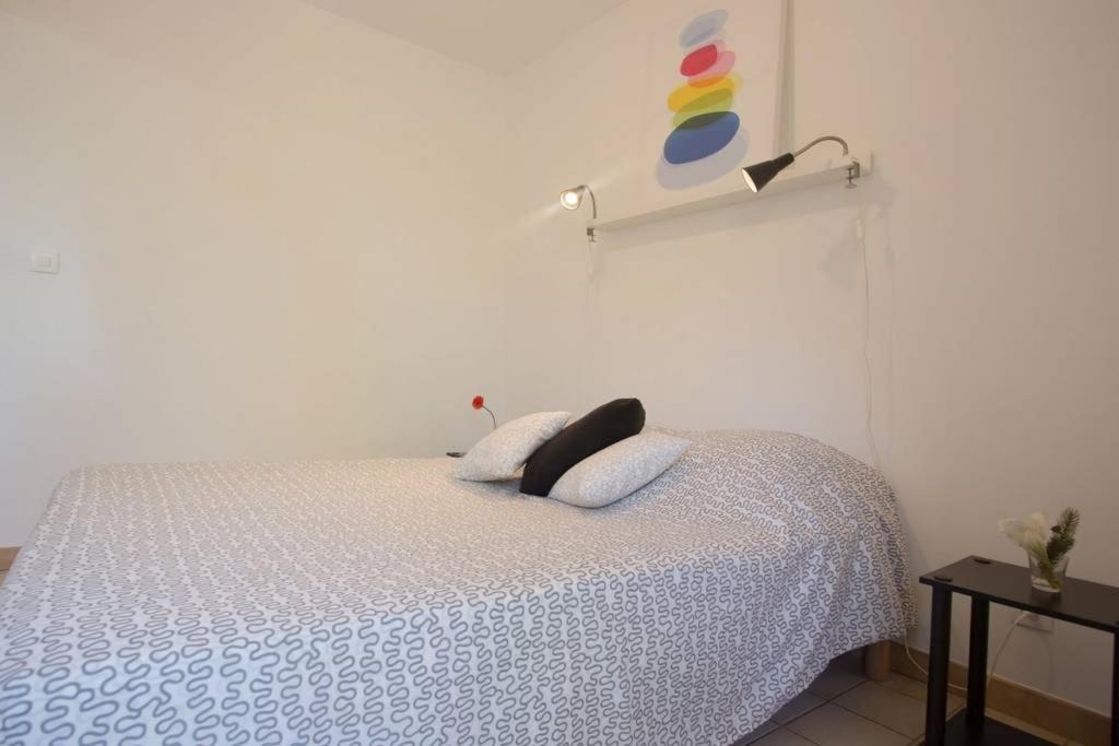 a bedroom with a white bed with a black pillow at Dans un écrin de verdure in Hyères