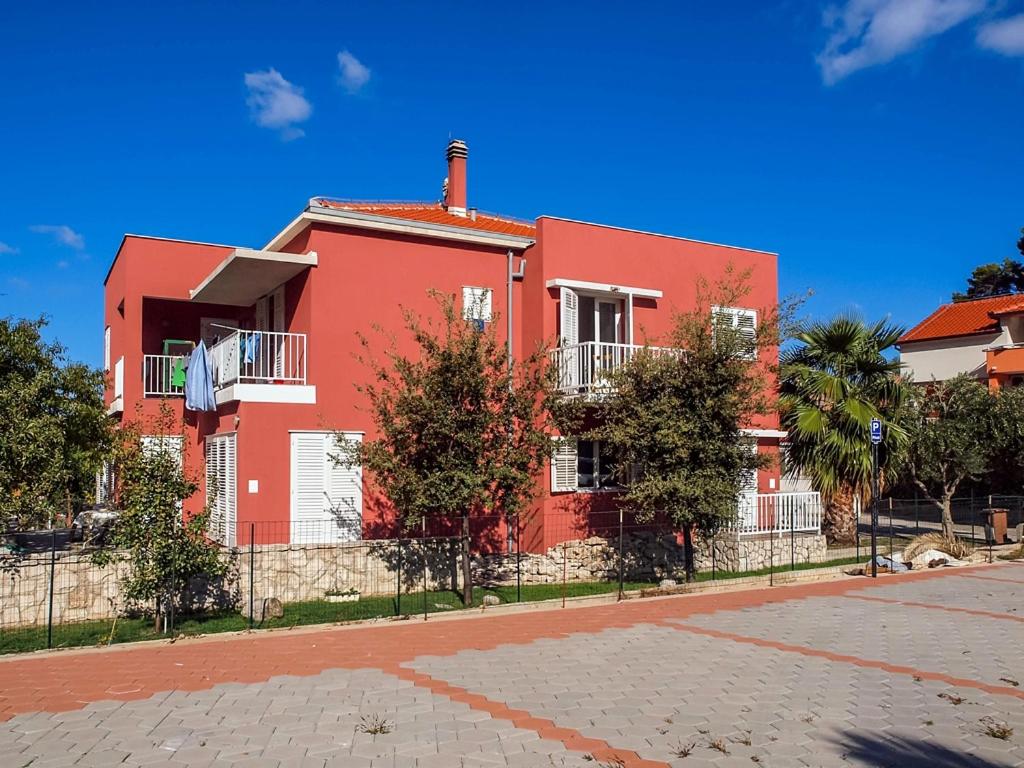 ein rotes Haus an der Seite einer Straße in der Unterkunft Apartmani Miljak Trpanj in Trpanj