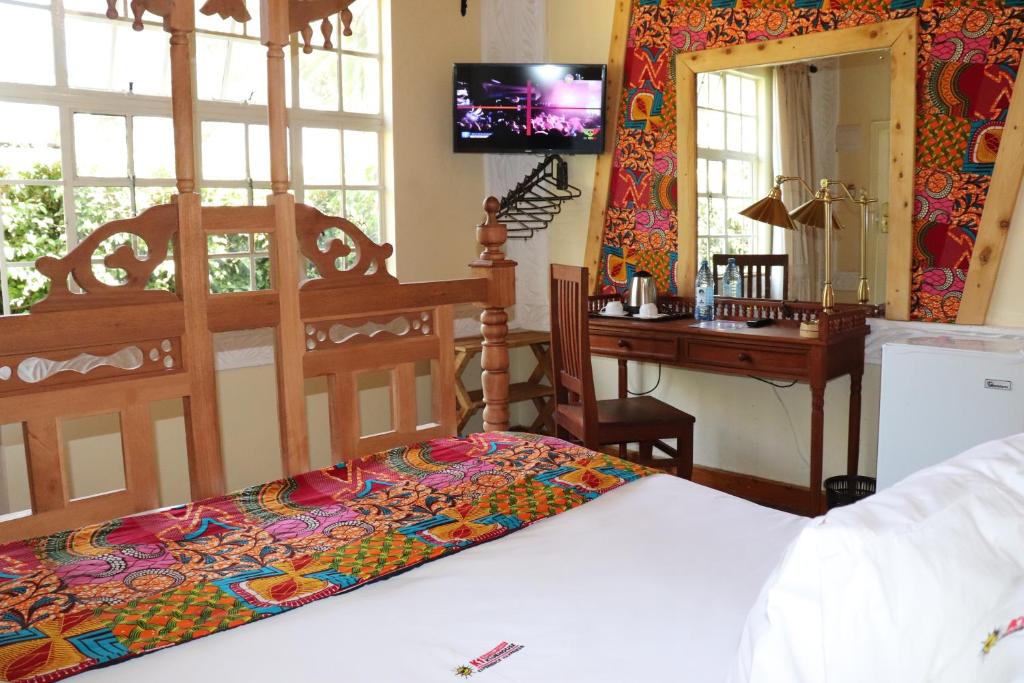 een slaapkamer met een bed, een bureau en een televisie bij Parklands Shade Hotel in Nairobi