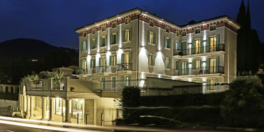 un grande edificio bianco con luci accese di notte di Mefuta Hotel a Gardone Riviera