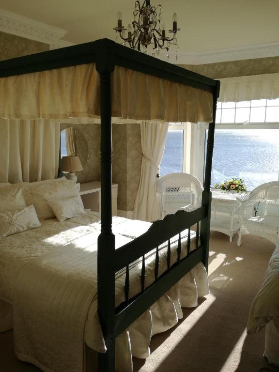 a bedroom with a canopy bed with a view of the ocean at Captains Lodge in Newbiggin-by-the-Sea