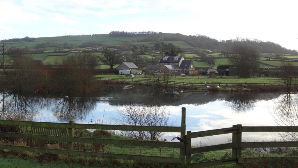 a view of a village with a fence and a lake at Spillers Farm in Axminster