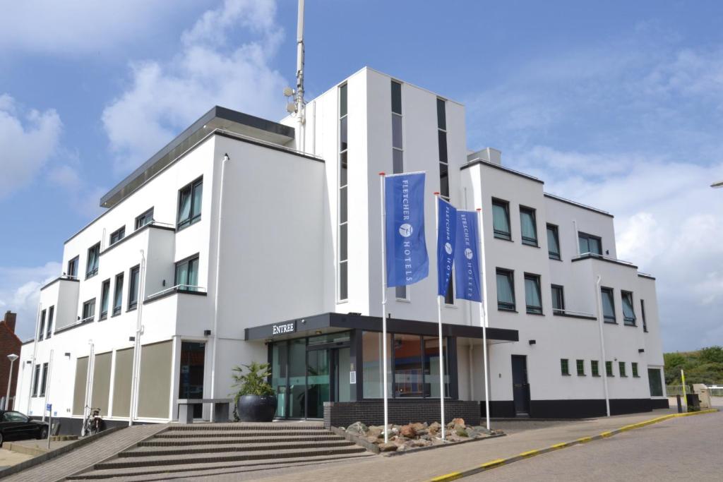 a white building with blue signs in front of it at Fletcher Hotel - Restaurant Elzenduin in Ter Heijde