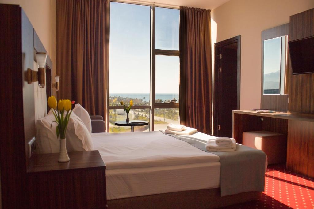 バトゥミにあるLegend Business Hotel Batumiのベッドと大きな窓が備わるホテルルームです。