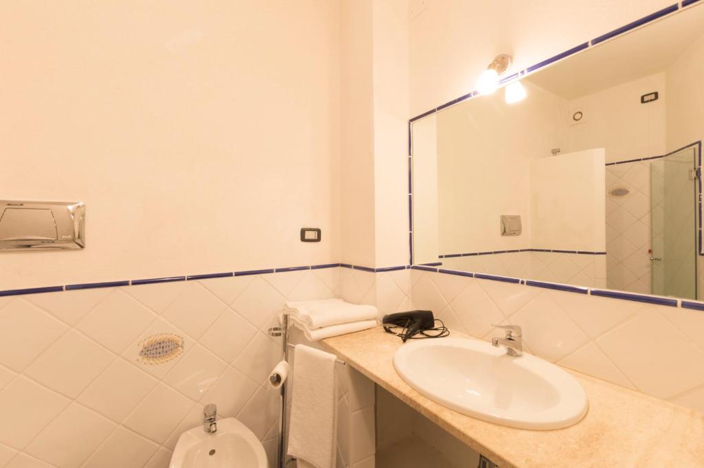 a bathroom with a sink and a toilet and a mirror at Sa Tirìa in Chia