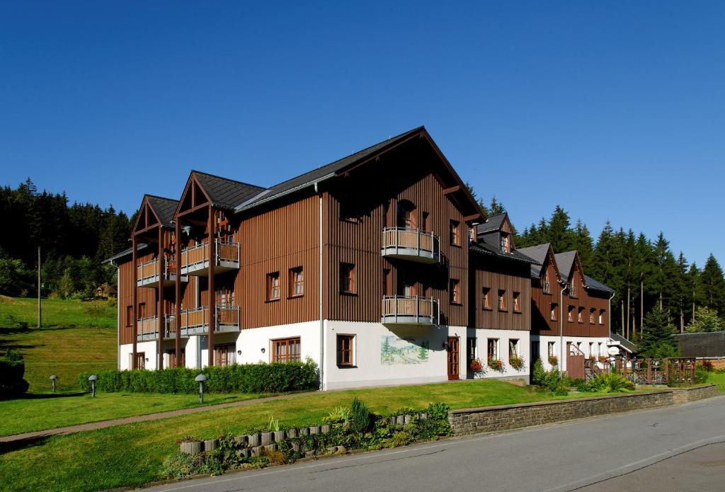 un grand bâtiment marron et blanc sur le côté d'une route dans l'établissement Hotel Schwarzbeerschänke Pobershau, à Pobershau