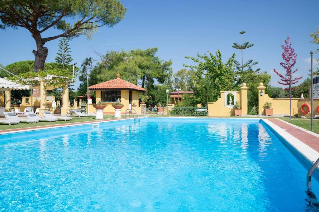 a swimming pool with blue water in front of a house at Hotel Villa Rita in Paestum