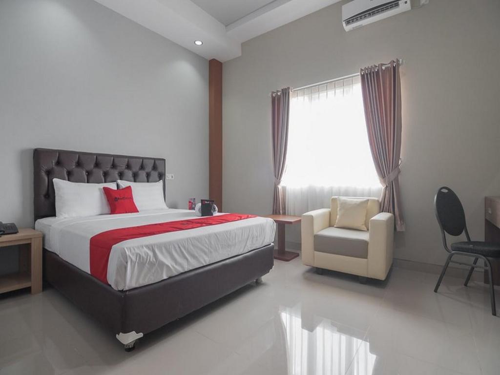 a bedroom with a bed and a chair and a window at RedDoorz near Islamic Center Samarinda in Samarinda