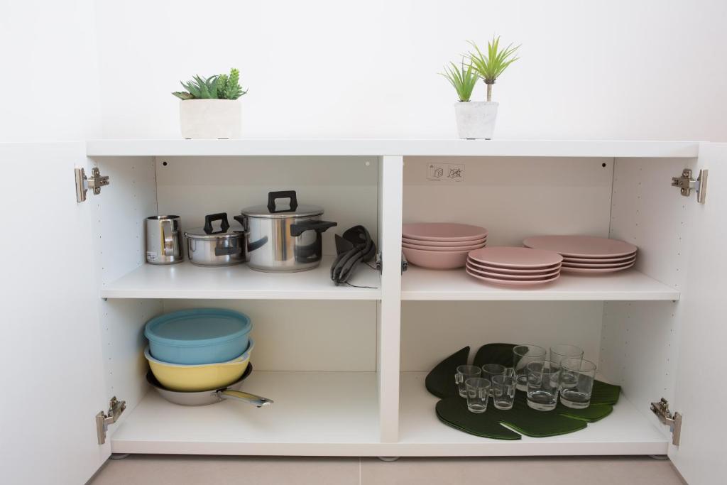 a white pantry with dishes and pots and pans at Cocor Suites & Design in Naples