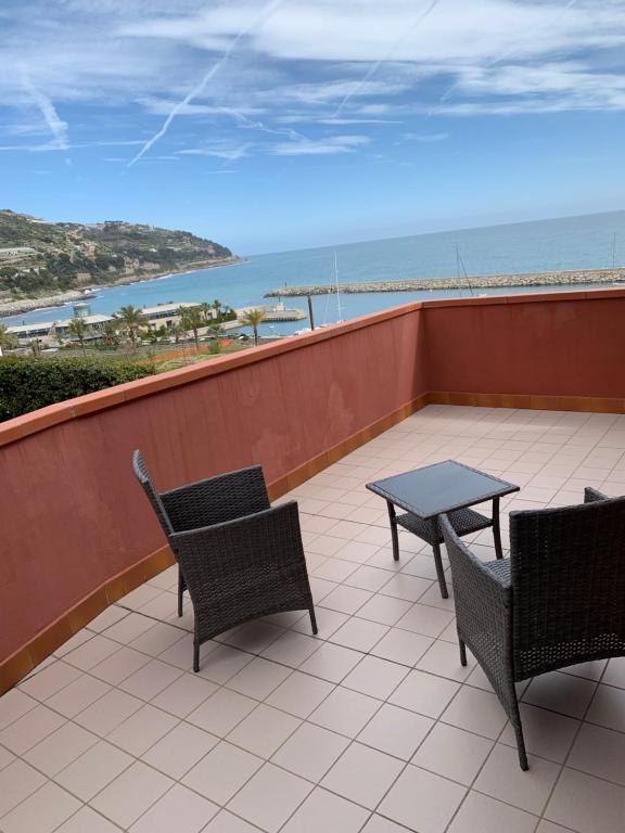 a patio with chairs and a table and a view of the ocean at Baia dei Gabbiani in San Lorenzo al Mare