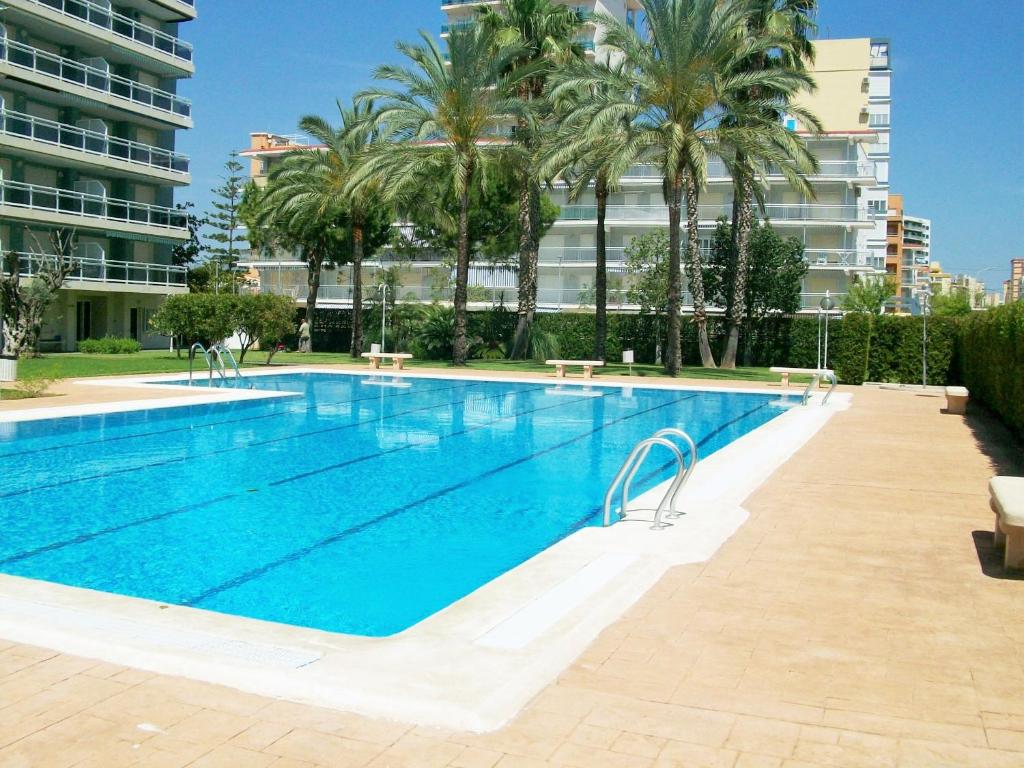 a large swimming pool with palm trees and a building at FLORESTA GANDIA - Solo Familias in Playa de Gandia