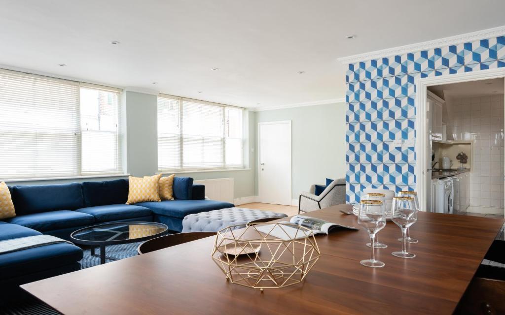 a living room with a blue couch and a table at The Kensington Palace Mews - Bright & Modern 6BDR House with Garage in London