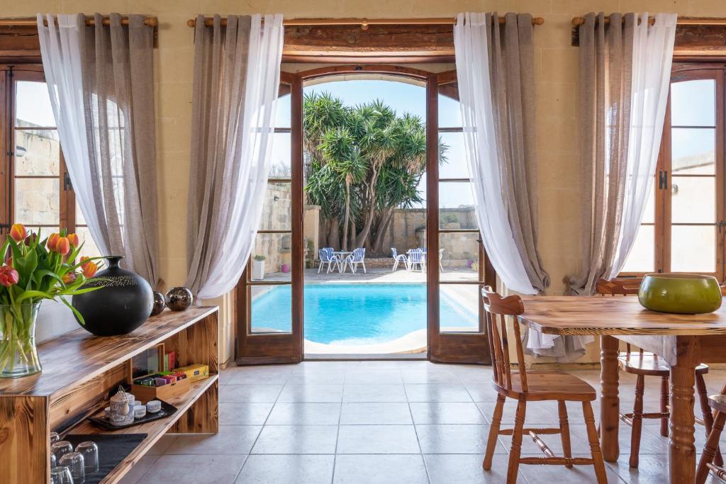 uma sala de jantar com uma mesa e uma piscina em Mood Farmhouse B&B em Għarb