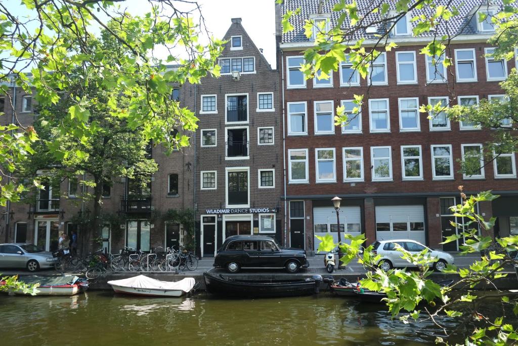 een kanaal met boten en auto's geparkeerd voor gebouwen bij B&B Wladimir Studios in Amsterdam