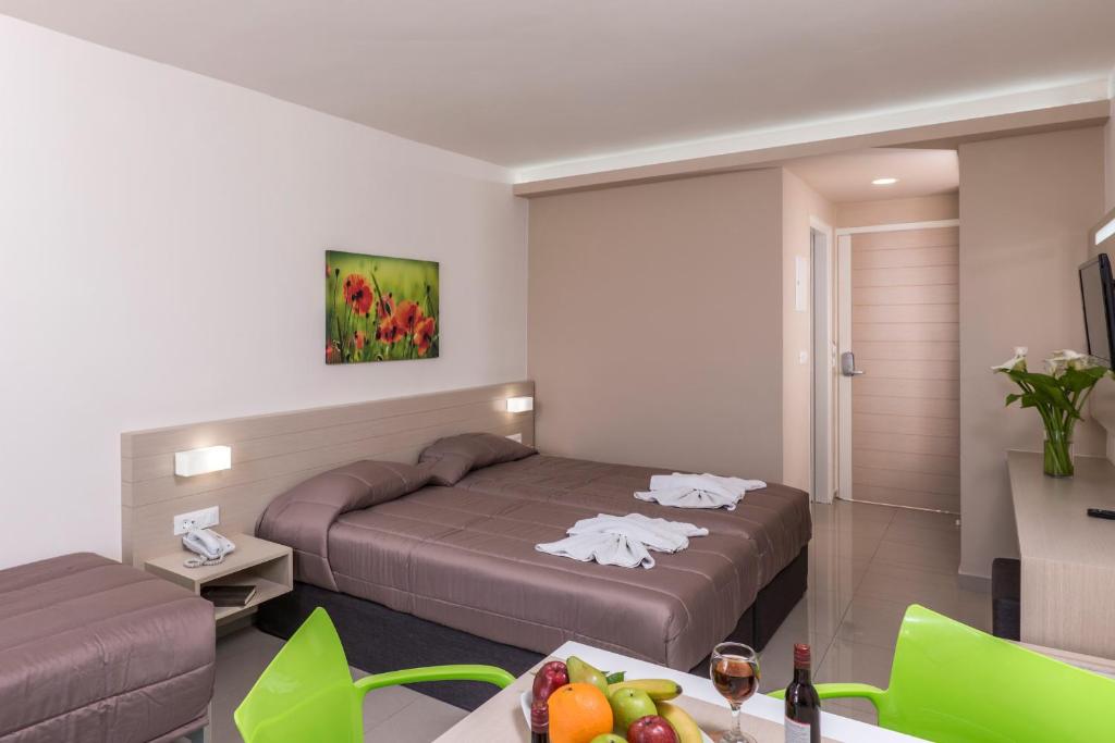 a hotel room with two beds and a table with fruit at Atrion Resort Hotel in Agia Marina Nea Kydonias