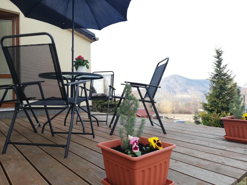 a deck with chairs and a table and an umbrella at Ubytování pod Stolovou in Kunčice pod Ondřejníkem