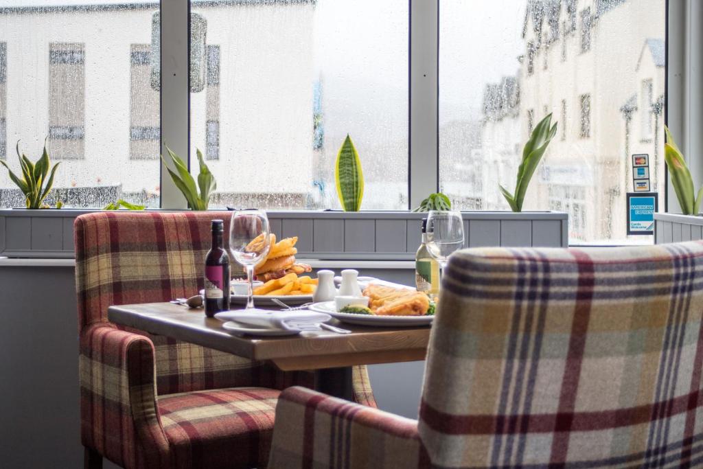 a table with a plate of food and two chairs at Kyle Hotel ‘A Bespoke Hotel’ in Kyle of Lochalsh