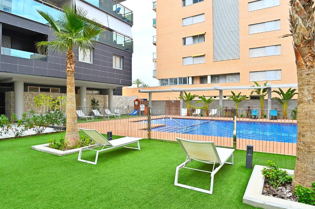 a yard with chairs and a swimming pool in a building at MyFlats Abedules in El Campello