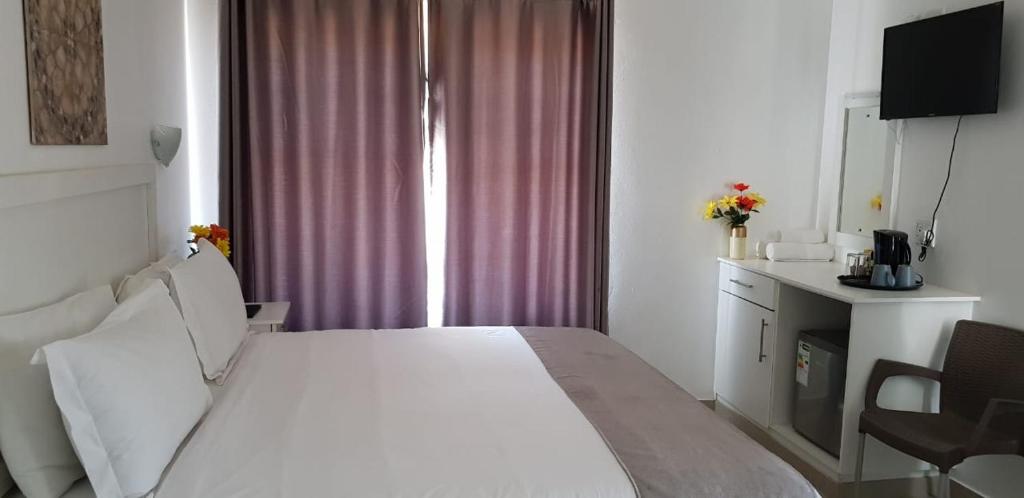 ダーバンにあるRoyal Ushaka Durban Northの白いベッドと窓が備わるホテルルームです。