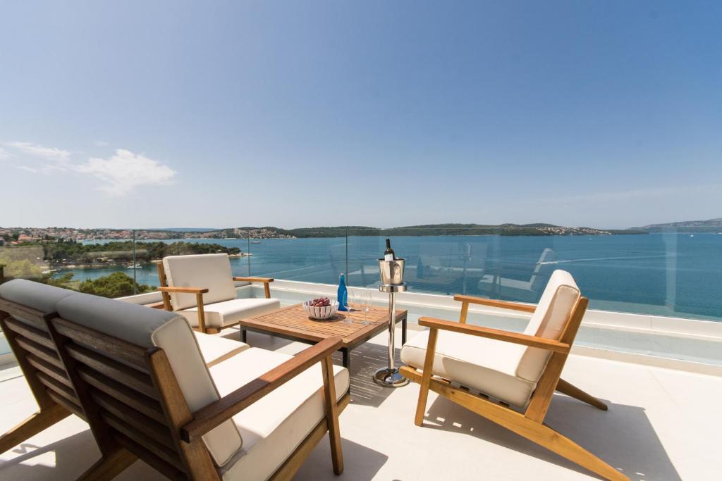 un patio con sillas y una mesa con vistas al agua en Seafront Luxury Apartments Fun, en Trogir