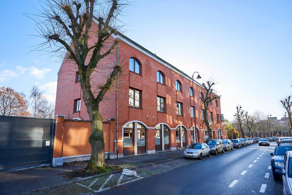 un edificio di mattoni rossi con auto parcheggiate sul lato di una strada di Generation Europe Youth Hostel a Bruxelles