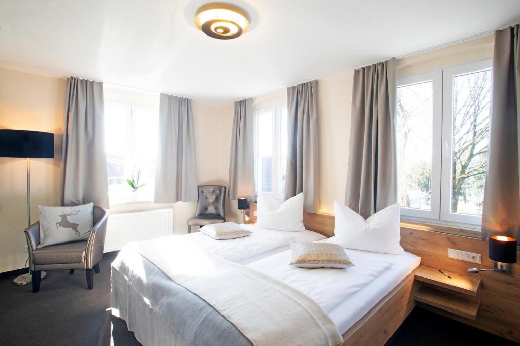a bedroom with a large white bed with windows at Hotel & Gutsgasthaus Köberle in Lindau