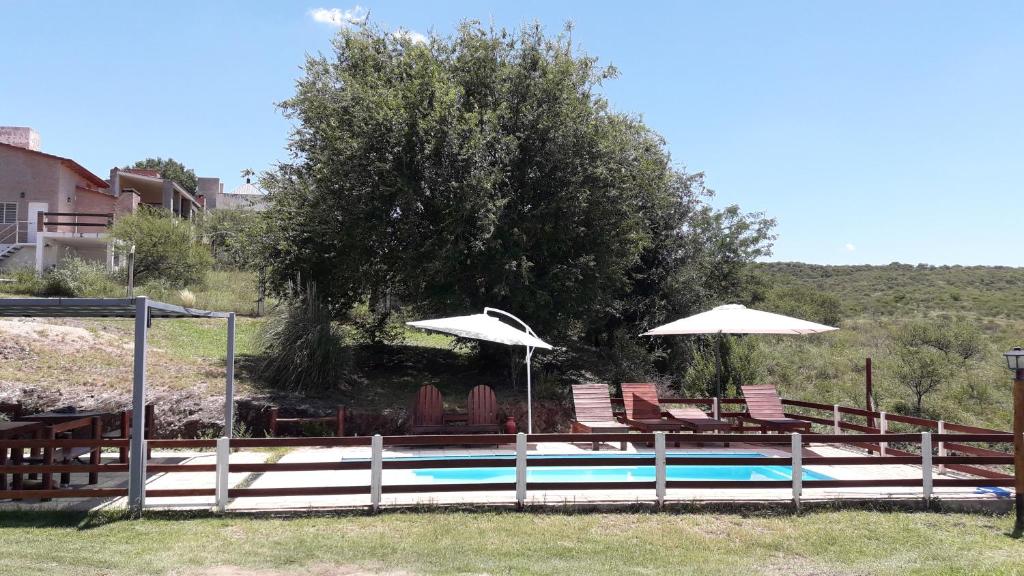 a swimming pool with chairs and umbrellas next to at Terrazas de mayu in Villa Icho Cruz