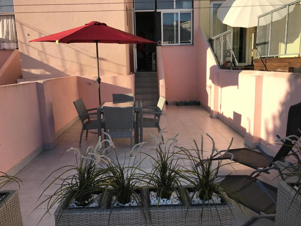 eine Terrasse mit einem Tisch mit einem Sonnenschirm und Pflanzen in der Unterkunft Sete Rios, Near Zoo Lisboa/ free Wifi in Lissabon