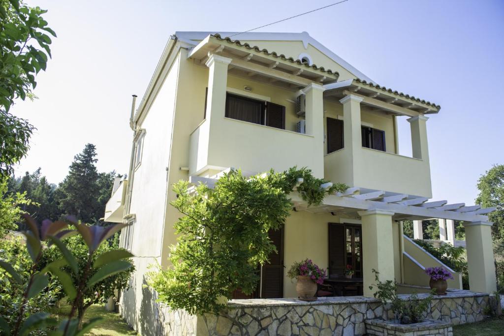 una casa bianca con un muro di pietra di Miltiadis Apartments Spiti Miltiadis ad Agios Georgios Pagon