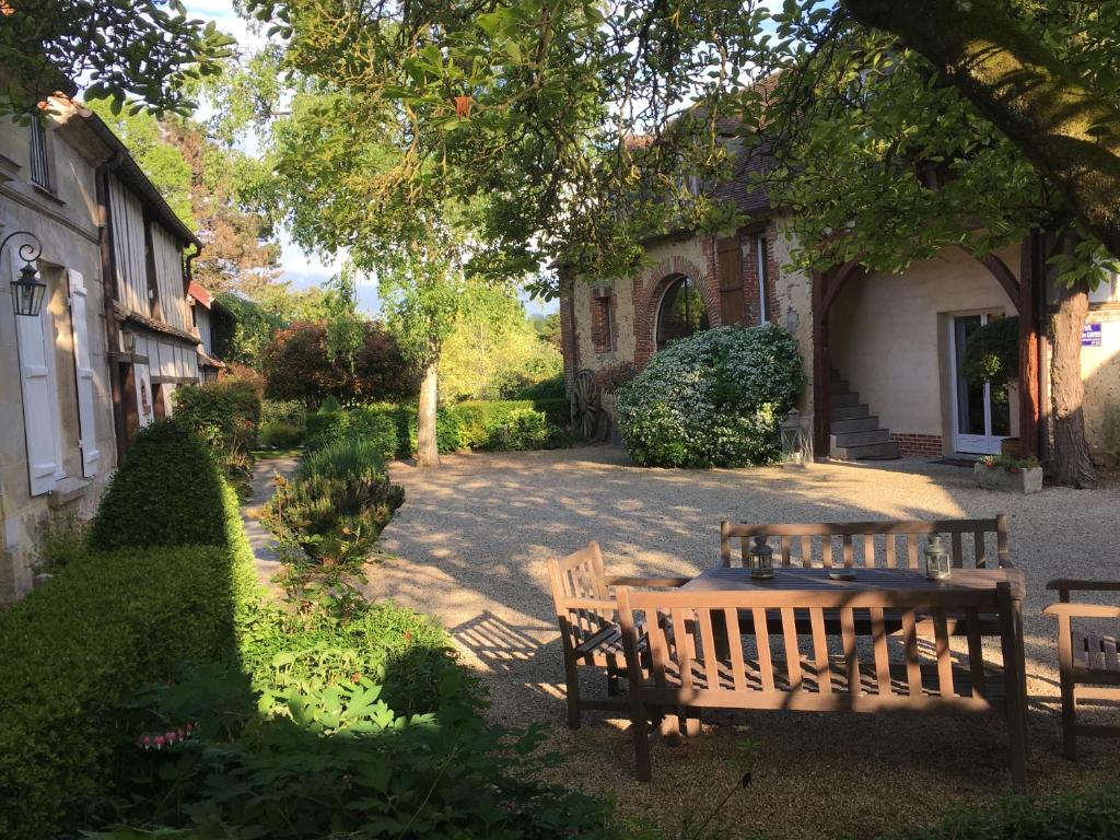 une table et des chaises en bois sous un arbre dans l'établissement Le Puits D'Angle, à Thibivillers