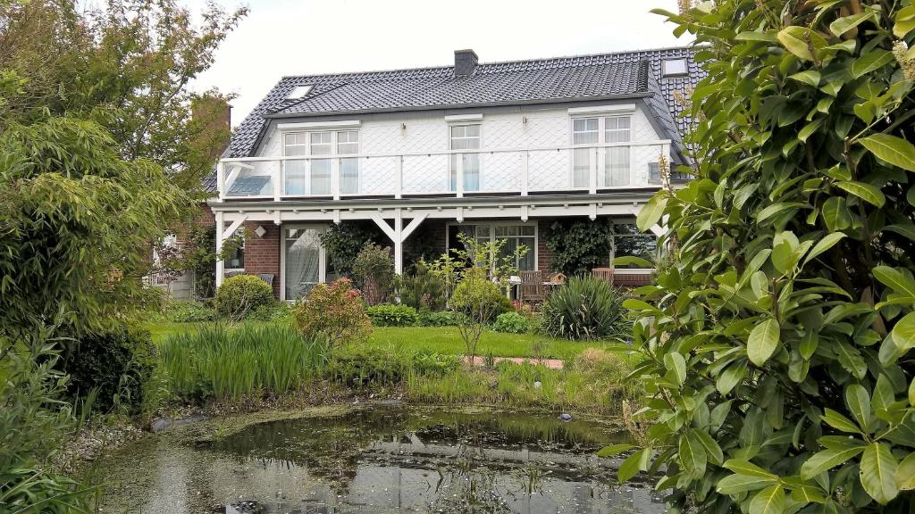 ein Haus mit einem Teich davor in der Unterkunft Ferienwohnung Nordseewatt in Wremen