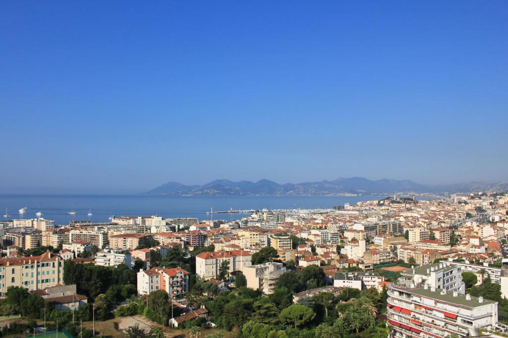 a view of a city with the ocean in the background at Hotel Cannes Montfleury in Cannes