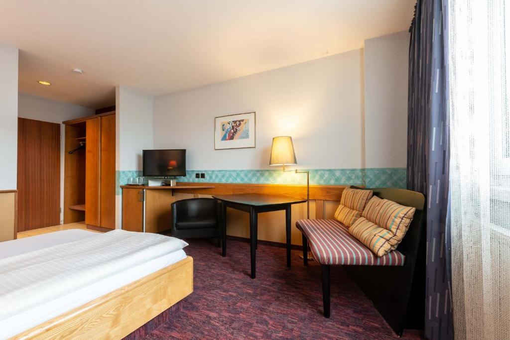 a hotel room with a bed and a desk at enjoyHotel garni Korntal Stuttgart in Stuttgart