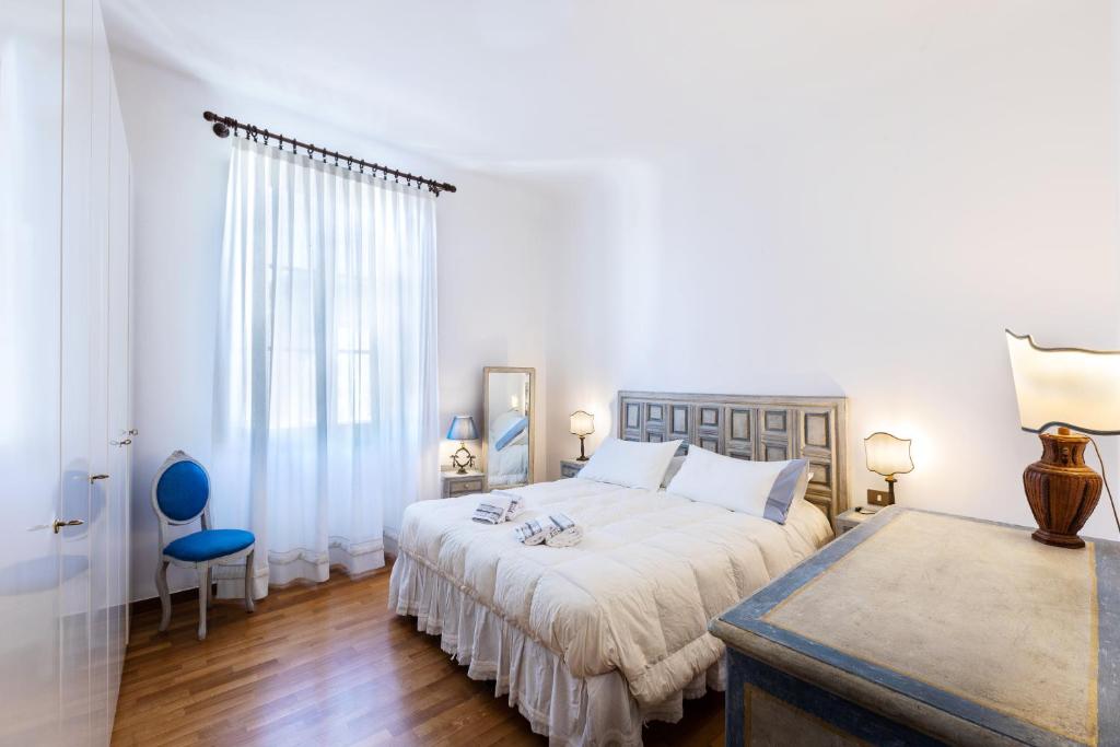 a white bedroom with a large bed and a blue chair at Fiesole's cozy Apartment 1 in Fiesole