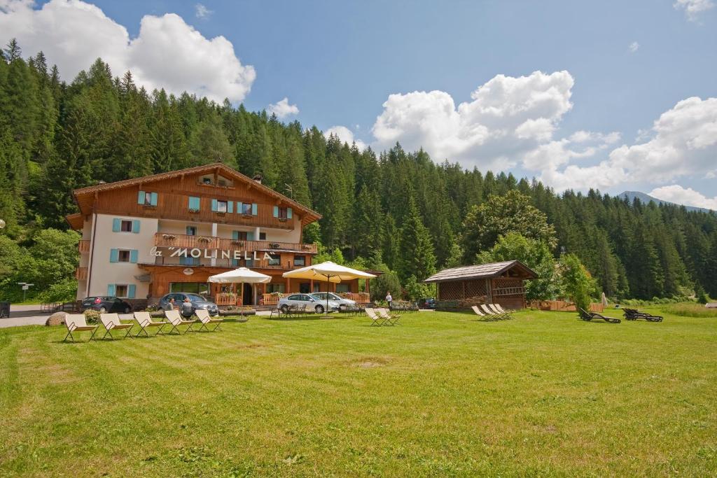 a large building in a field in front of a mountain at Hotel La Molinella in Soraga