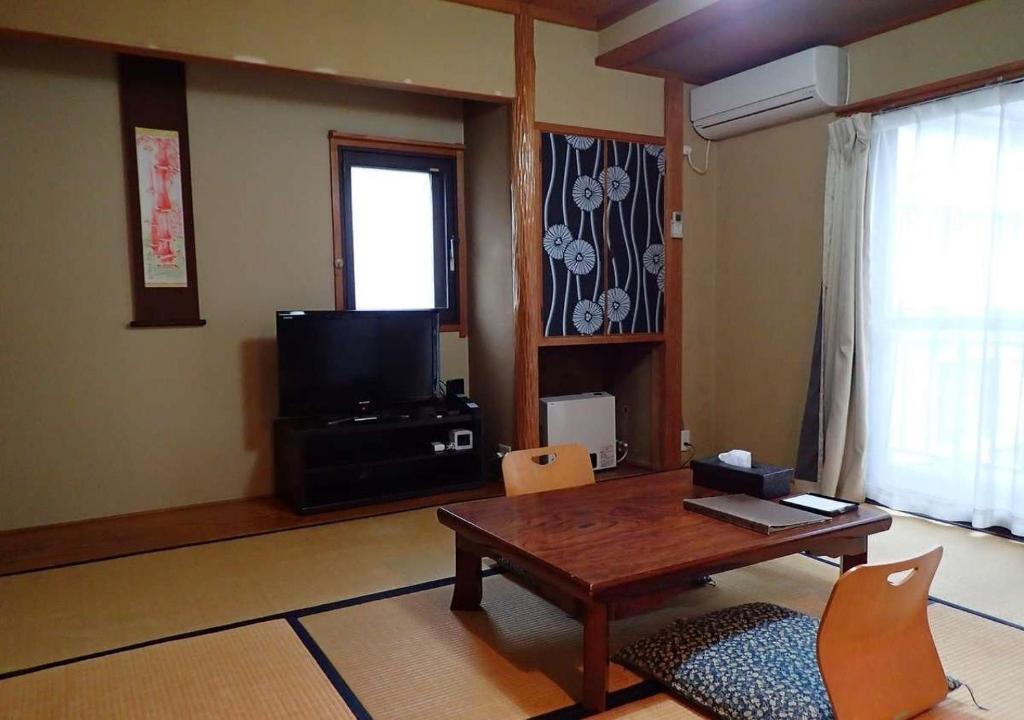 uma sala de estar com uma mesa e uma televisão em Address Nozawa Japanese Room / Vacation STAY 22751 em Nozawa Onsen