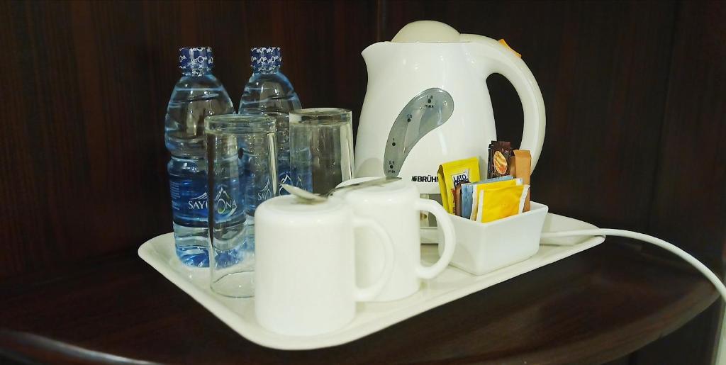 a shelf with a tea kettle and bottles on it at Hotel Blue Sapphire in Dar es Salaam