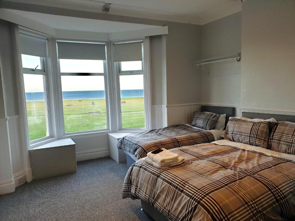 a bedroom with two beds and a large window at Cara Guesthouse in Whitley Bay