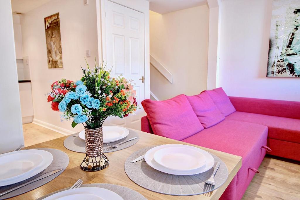 a living room with a pink couch and a table at Abbey House in Paisley