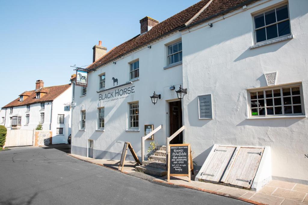 um edifício branco com um sinal em frente em Black Horse em Amberley