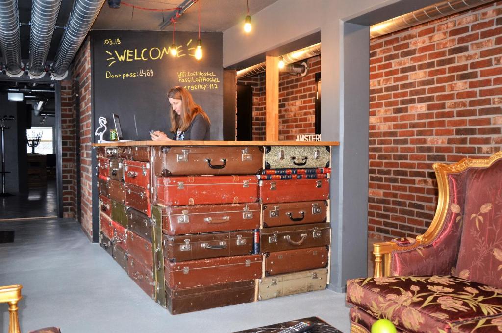 a woman sitting at a counter with several stacks of suitcases at Loft Family Hotel in Imatra