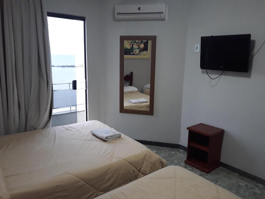 a bedroom with a bed and a mirror and a television at Hotel Nolasco in Macaé
