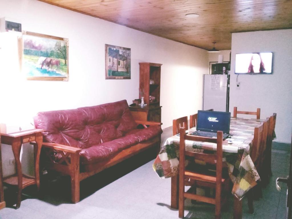 sala de estar con sofá y mesa con ordenador portátil en La Elegida con quincho y cochera en Esquel