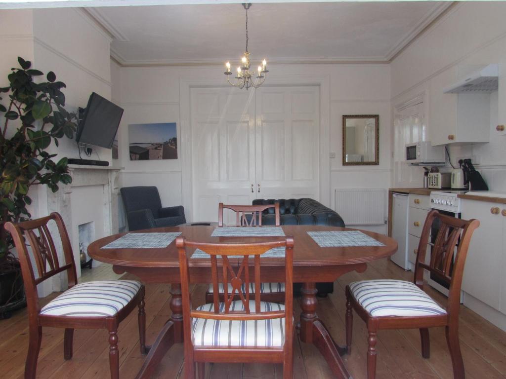 a kitchen and dining room with a table and chairs at The Garden Apartment in Weymouth