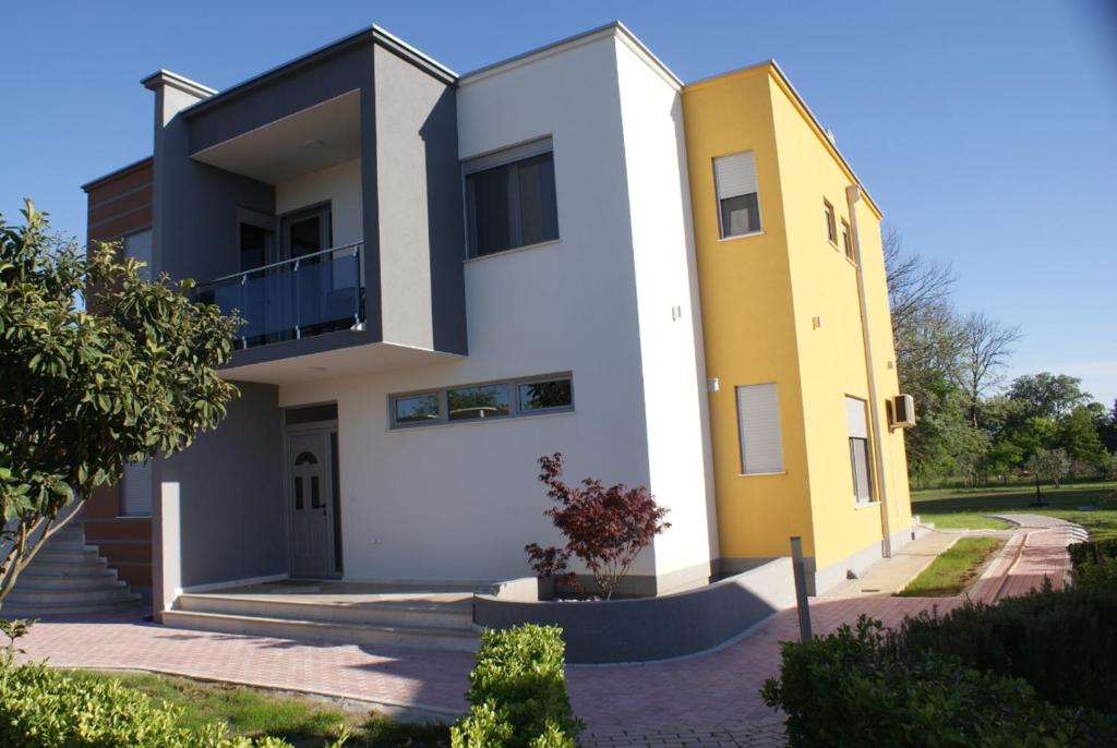 a large white and yellow house with a staircase at Helena Apartments in Ulcinj