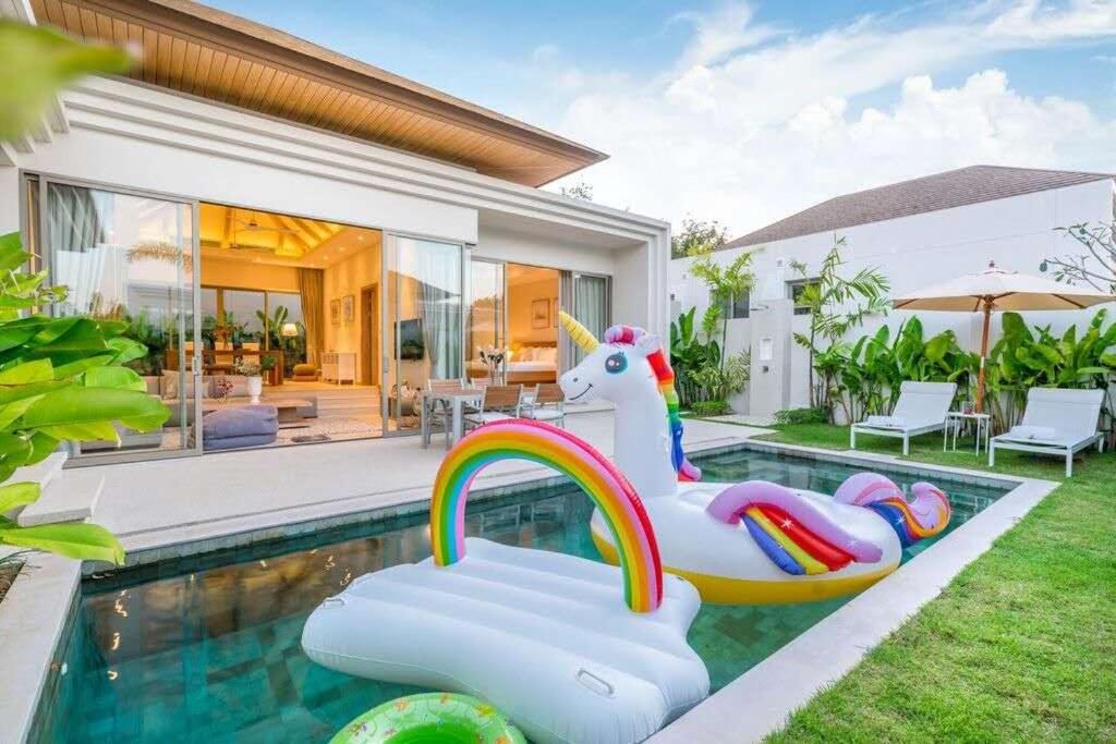 a swimming pool with a unicorn pool noodle in front of a house at Trichada Tropical in Bang Tao Beach