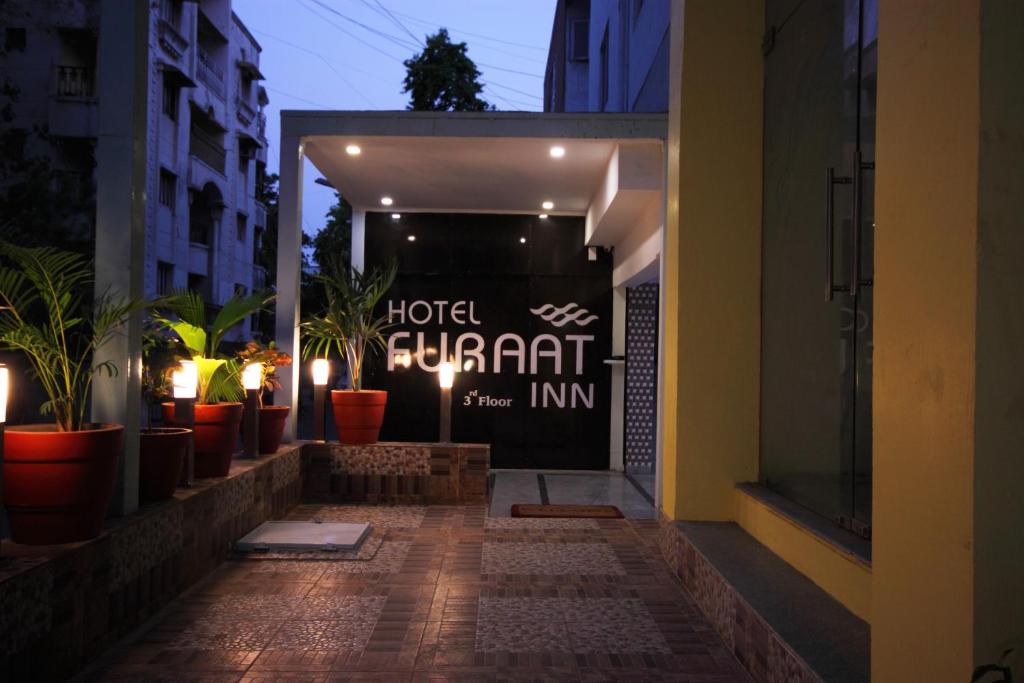 a hotel entrance with potted plants in a building at Hotel Furaat Inn in Ahmedabad