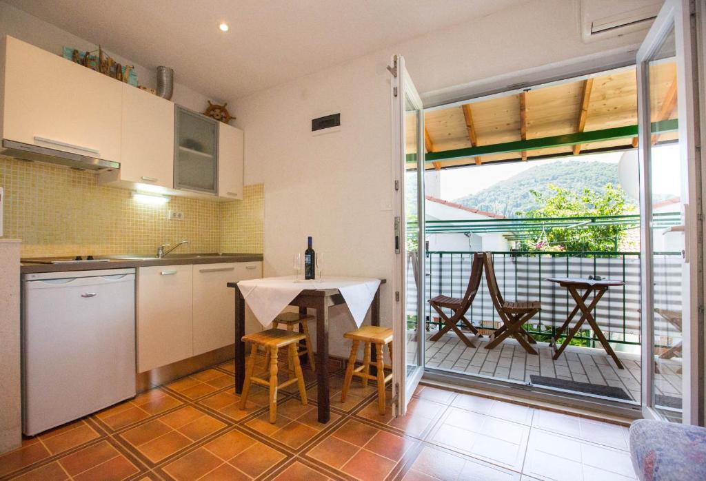 cocina con mesa y sillas y balcón en Anita Apartments, en Dubrovnik