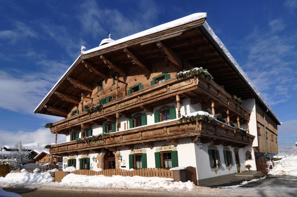 a building with a wooden roof in the snow at Kaiserpension Müllnerhof in Oberndorf in Tirol