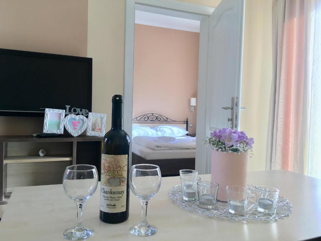 a bottle of wine sitting on a table with glasses at Palvile Apartmani in Palić